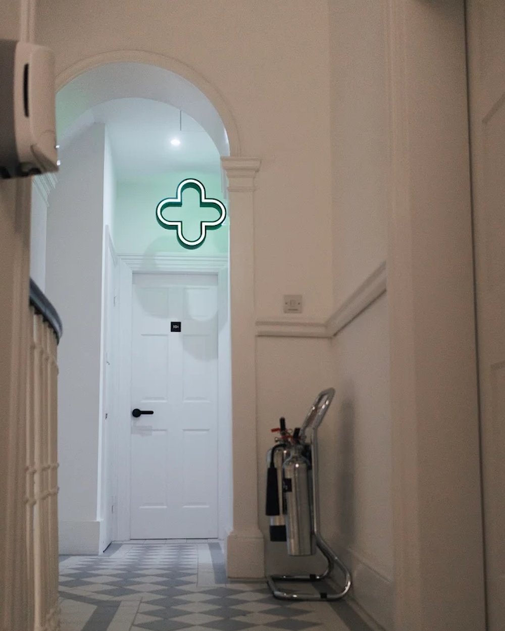 The corridor to our in-house pharmacy — the green cross above a period archway