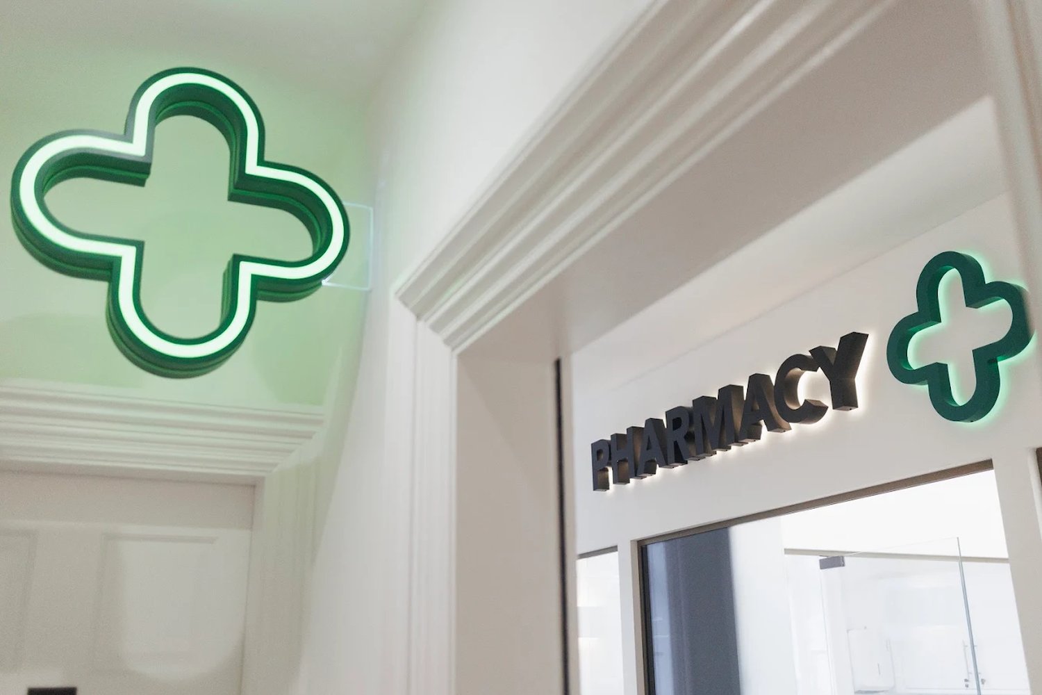 The pharmacy entrance at 82 Harley Street — backlit lettering and the green cross